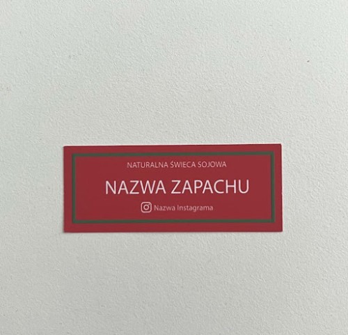 Czerowno-zielona naklejka świąteczna na świece sojową z białymi napisami na białym tle.