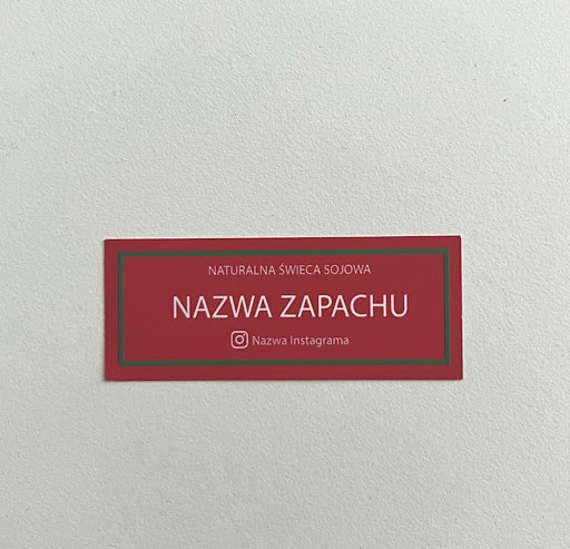 Czerowno-zielona naklejka świąteczna na świece sojową z białymi napisami na białym tle.